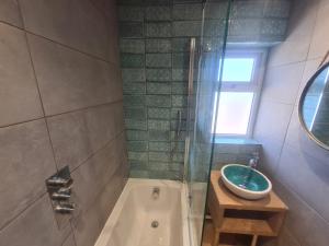a bathroom with a tub and a sink and a shower at 2 Fernleigh Villas in Perranporth +20 photos