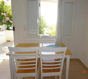 mesa de comedor con 2 sillas y ventana en Antoninis Village, en Houlakia