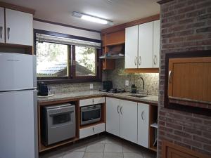 una cocina con armarios blancos y una pared de ladrillo en Casa de Família - Quinta da Serra, en Canela