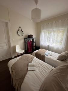 een slaapkamer met 2 bedden, een stoel en een raam bij Le Gîte de la Maison Blanche in FlÃ©chin