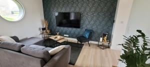 a living room with a couch and a tv on a wall at Célest' Inn in Cléder