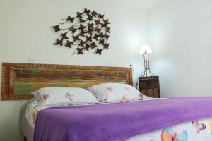 Una cama con una manta púrpura y almohadas. en Acapela Hospedagem, en Ouro Preto
