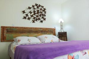 a bed with a purple blanket and pillows on it at Acapela Hospedagem in Ouro Preto
