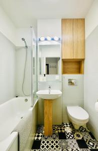 華沙的住宿－Eastside Warsaw Apartment，浴室配有盥洗盆、卫生间和浴缸。