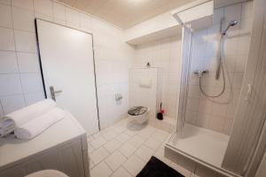 uma casa de banho branca com um chuveiro e um WC. em Am Waldrand nähe Nürnberg Messe em Schwarzenbruck
