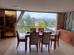 a dining room with a table and chairs and a large window at Depar Rio Cuenca - Confortable in Cuenca