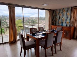 a dining room with a table with chairs and a large window at Depar Rio Cuenca - Confortable in Cuenca