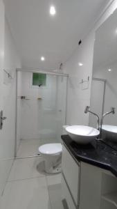 La salle de bains blanche est pourvue d'un lavabo et de toilettes. dans l'établissement Apartamento Alto Padrão próximo Agrishow, à Ribeirão Preto
