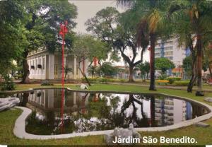 a park with a pond in front of a building at Studio quartzo cinza - centro in Campos dos Goytacazes