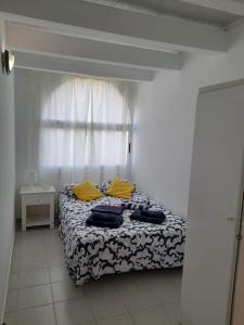 sypialnia z łóżkiem z żółtymi poduszkami i oknem w obiekcie amarilla terrace w Aronie