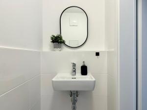a white bathroom with a sink and a mirror at Modern Haven - Near Klinik Floridsdorf in Vienna