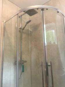 La salle de bains est pourvue d'une douche avec une porte en verre. dans l'établissement Just Stay Wales - Marshmallow Cottage, Oxwich, à Swansea