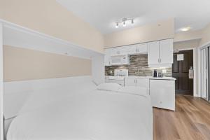 a white kitchen with white cabinets and white appliances at Alpenglow Lodge Studio with park view by MVA in Whistler