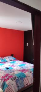 ein Schlafzimmer mit einem Bett mit einer roten Wand in der Unterkunft Ipiales Puerta de Oro Alborada in Ipiales