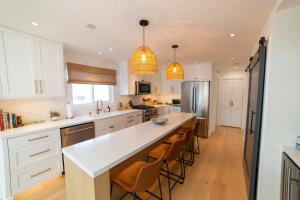 a kitchen with white cabinets and a large island with bar stools at The Harbor Lookout in Newport Beach