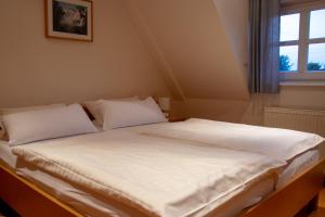 - un lit avec des draps et des oreillers blancs dans l'établissement Landhaus Lastrup, à Lastrup
