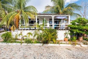 a white house with palm trees in front of it at La Bocana Palm House in Santa Cruz Huatulco