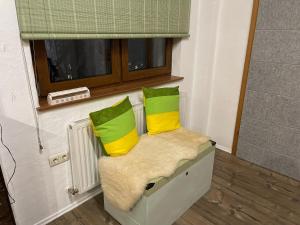 Una silla con dos almohadas verdes y amarillas. en Süße Wohnung Privatvermieter, en Schwaz