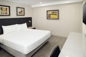 een slaapkamer met een wit bed en een bureau bij Skyview Motel in Fort Lee