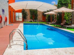 a swimming pool with an umbrella next to a house at Hampton Inn & Suites by Hilton Aguascalientes Aeropuerto in Aguascalientes