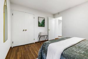 a white bedroom with a bed and a chair at Mid-Century-Modern Airport Home in Sacramento