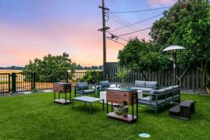 einen Garten mit Stühlen, Tischen und einem Sonnenschirm in der Unterkunft Mid-Century-Modern Airport Home in Sacramento