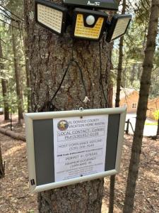 une caméra sur un arbre avec un signe sur celui-ci dans l'établissement Cabin in the Trees - Hot Tub, à Pollock Pines