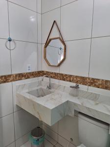 uma casa de banho com um lavatório em mármore e um espelho. em Girassol Pousada em Extremóz