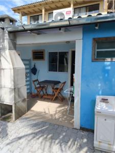 a blue house with a table and chairs on a patio at QUARTO COM COZINHA E CHURASQUEIRA INDIVIDUAL. in Passo de Torres