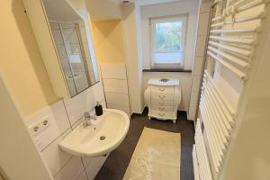 a white bathroom with a sink and a mirror at "Zur Gelassenheit" in Jugendstilvilla Sonnenschein in Stolberg +6 photos