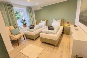 a living room with two beds and a chair and a window at "Zur Gelassenheit" in Jugendstilvilla Sonnenschein in Stolberg