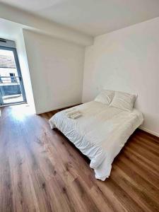 a bedroom with a white bed and a wooden floor at Magnificent apartment Paris Bagnolet 302 in Bagnolet