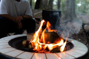 un hombre sentado al lado de un fuego en un círculo en Sunland O66 - Vacation STAY 72793v en Saikubo