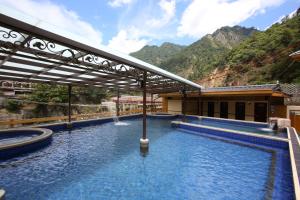 a resort with a swimming pool with mountains in the background at Utopia Holiday Hotel in Heping