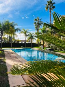 a swimming pool with palm trees and a building at Casa André - 3 Bedroom Roda Golf apartment nearby entrance and clubhouse in Roda