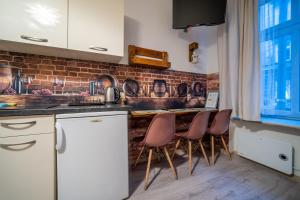 a kitchen with white cabinets and a brick wall at Apartamenty Idylla in Krakow