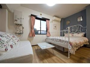 a bedroom with a bed and a couch and a window at Mini Hotel Shinjuku Front - Vacation STAY 89788v in Tokyo