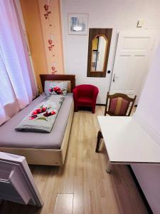 a small room with a bed and a red chair at Gästezimmer Siminciuc in Aachen