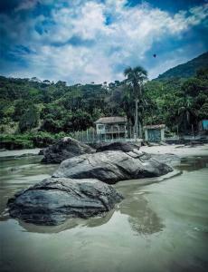 uma praia com uma grande rocha na água em Casa de praia da Terê em Peruíbe