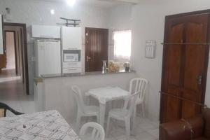 uma cozinha com uma mesa e cadeiras numa cozinha em Casa de praia da Terê em Peruíbe