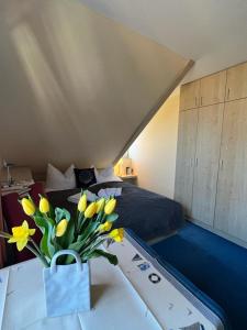 ein Schlafzimmer mit einem Bett und einer Vase aus Blumen auf einem Tisch in der Unterkunft Hotel-Pension Zur Mole in Wiek auf Rügen 
