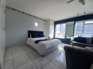 a bedroom with a large bed and a couch at Royal Classico Getaway in Strand Beach in Cape Town