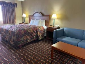 a hotel room with a bed and a blue chair at The Inn in Sault Ste. Marie