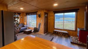 sala de estar con mesa, sofá y ventana en Cabaña - Granja Lago Frío, en Coyhaique
