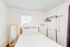 ein weißes Schlafzimmer mit einem Bett und einem Fenster in der Unterkunft The Sunset Pearl in Jacksonville Beach