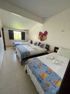 a hotel room with three beds and a window at Pousada Pura Vida in Barreirinhas