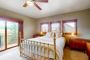 a bedroom with a bed with a ceiling fan and windows at Saddle Ridge Ranch in Granby