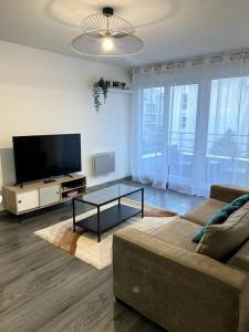 a living room with a couch and a flat screen tv at Cocon Eudenia - accès direct PARIS - 2 MIN RER - PARKING GRATUIT in Cergy