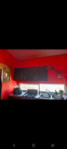 a kitchen with a stove and a red wall at Departamento Kassandra in Puerto Peñasco