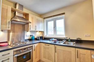 a kitchen with wooden cabinets and a sink and a window at The Beach House, With Secure Garage for Guest Use in Camber